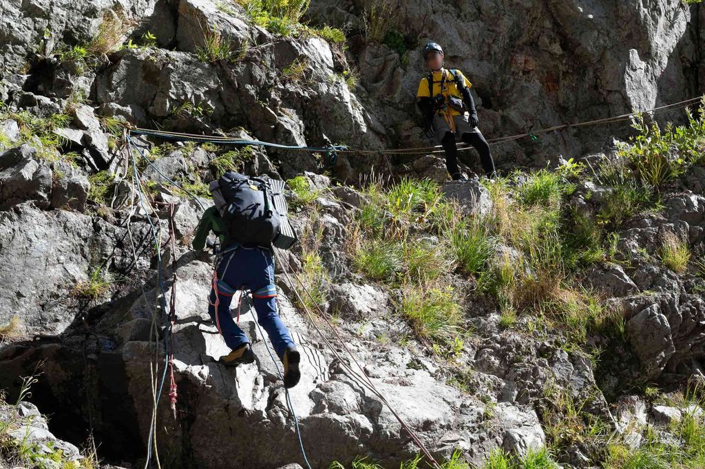ロープをつたって岩肌を登る登山者