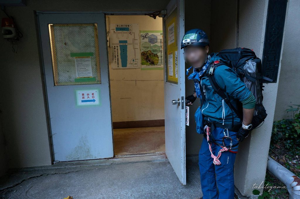 仙人谷ダム施設内へ続く扉を開ける登山者