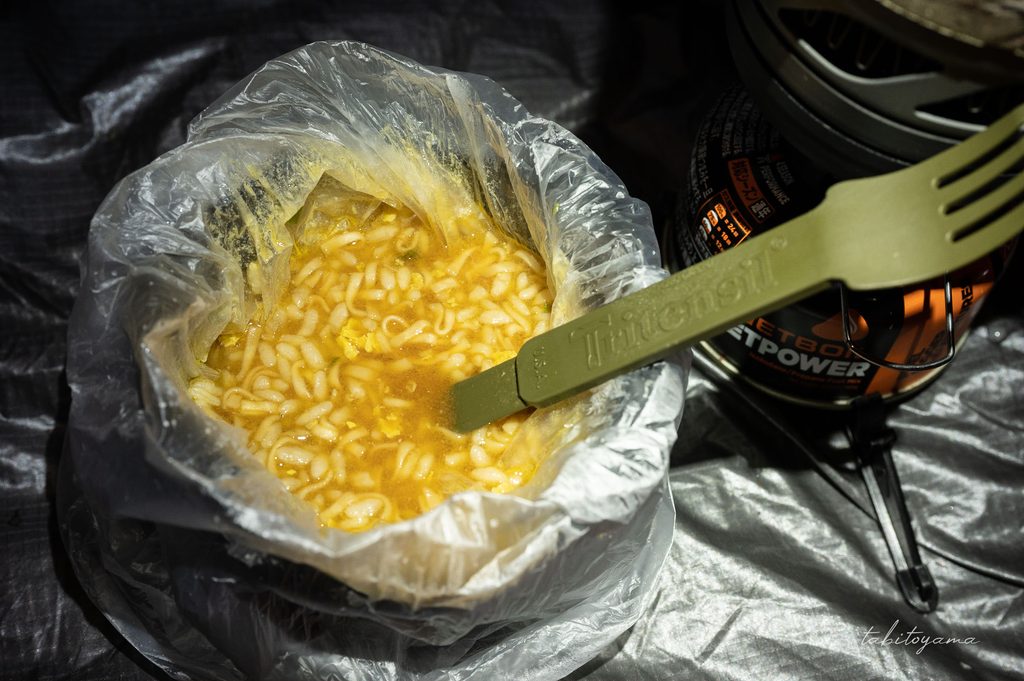 ポリ袋入りのカップヌードルぶっこみ飯にカトラリーが刺さっている