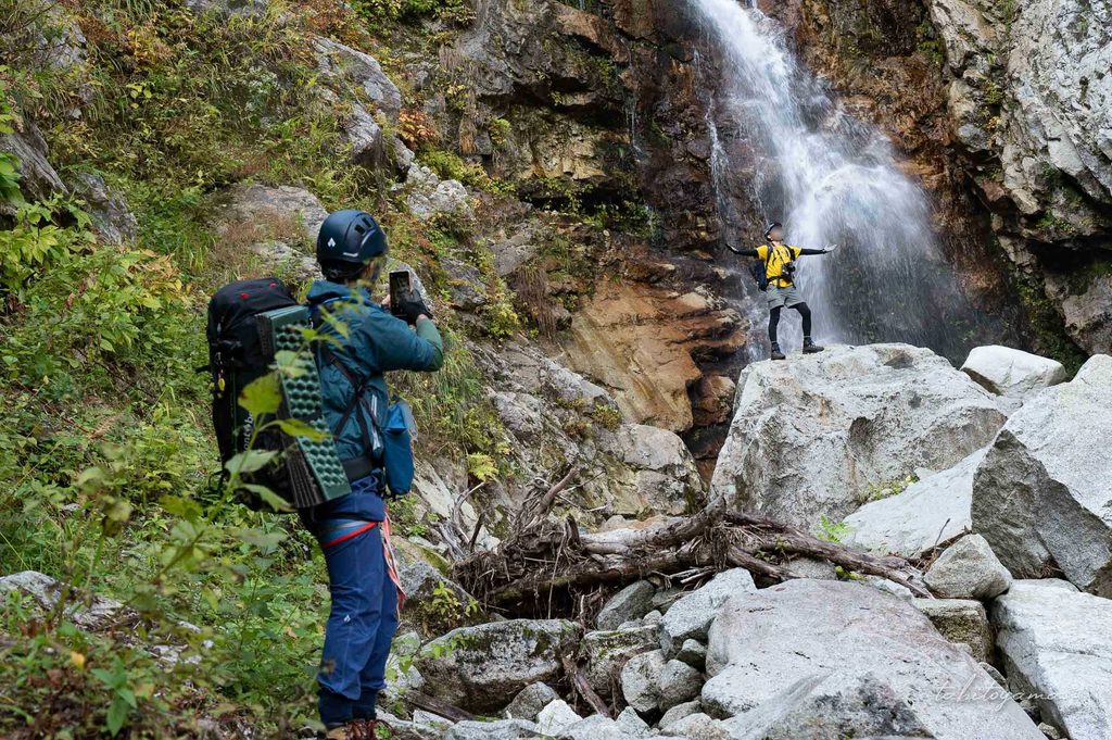 滝を前にポーズを取る登山者とそれを撮影する登山者