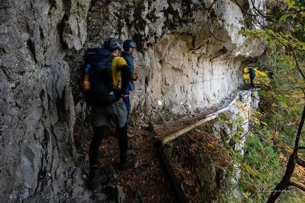 水平歩道の細い登山道を歩く登山者達