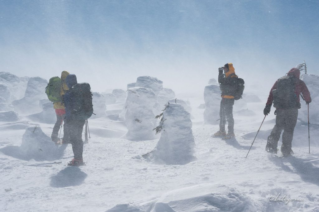 強風により雪が舞い上がる西吾妻山の山頂に集まる登山者たち