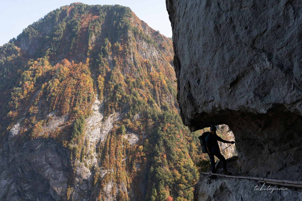 大太鼓周辺で安全確保をしながら通過する登山者と紅葉に色づく岩壁