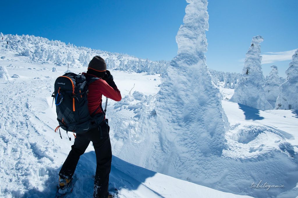樹氷に近いてカメラを構える登山者