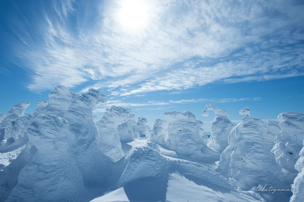 薄い雲が広がる青空の下に広がる樹氷群