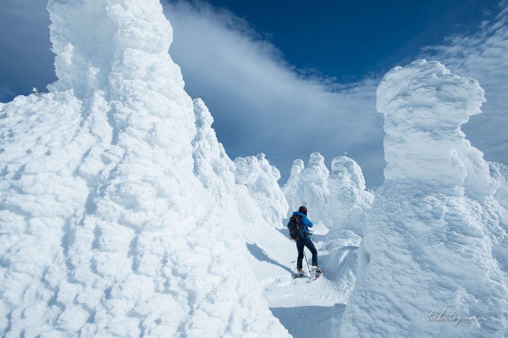 大きな樹氷の隙間の間を歩く登山者の姿